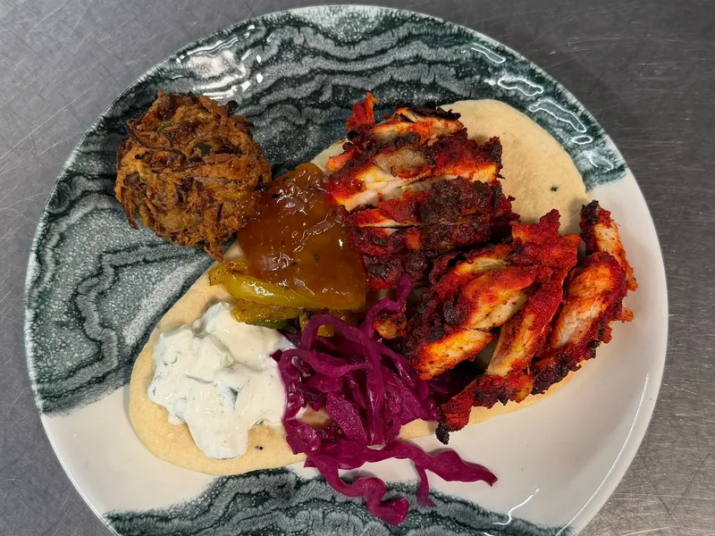 Spiced chicken on a flatbread with tzatziki and pickled red cabbage