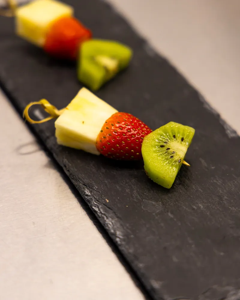 Pineapple, strawberry and kiwi fruit skewers on a slate