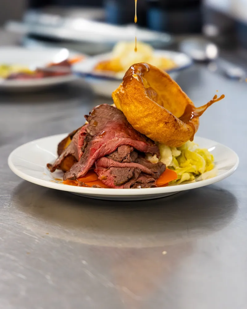 Roast beef with a Yorkshire pudding, gravy being poured on the pass
